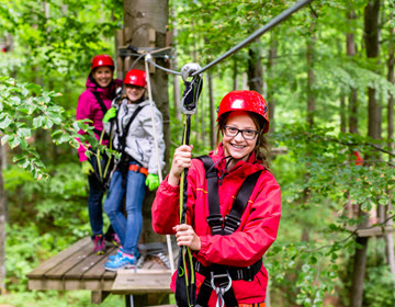 Smiling teenager doing treetop wires at family adventure camp